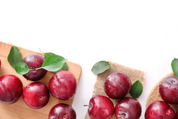 Fresh ripe plums, board and sackcloth on white background