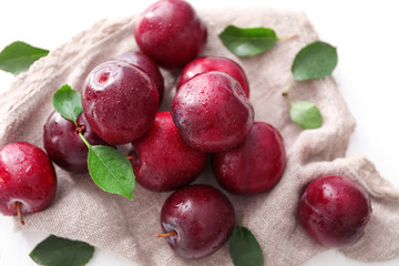 Fresh ripe plums and sackcloth on white background
