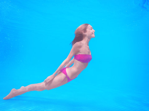 Beautiful Young Woman Swimming Under Water In Pool