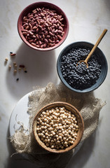 Garbanzo beans/chickpeas,kidney beans/rajma,black beans in individual ceramic bowls on a marble table on top view