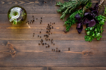 Bottle with organic oil with herbs ingredients on wooden background top view mockup