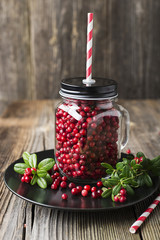 Bottle full of berries fresh ripe northern lingonberry with straws for a cocktail. The concept of healthy drinks from organic products. Top View