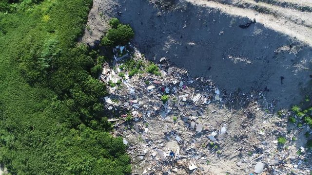 Aerial top down view of garbage recycling yard moving down fast while panning also showing green vegetation at side of garbage in urban areas garbage is collected and treated as municipal solid waste