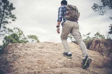 Hiker with backpack climbing rocky terrain. Focus on the boot