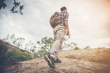 Hiker with backpack climbing rocky terrain. Focus on the boot