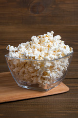 Popcorn in glass bowl on wooden background