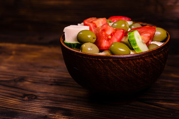 Greek salad in a bowl on wooden table