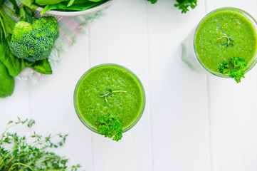Obraz premium Top view Fresh green Spinach smoothies in glass on the white wooden background. Healthy lifestyle concept. Selective focus. Flat lay. Copy space.