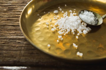 Salt in spoon and plate on wooden table