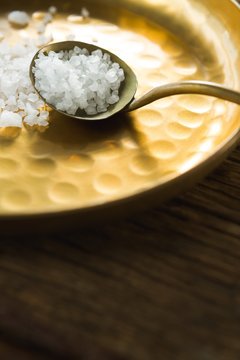 Salt in spoon and plate on wooden table