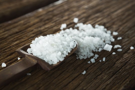 Salt in spoon on wooden table