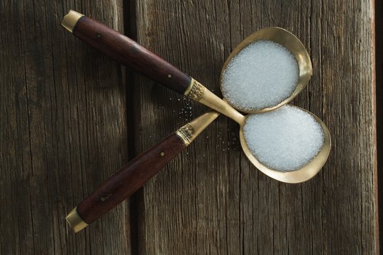 Salt in spoon on wooden table