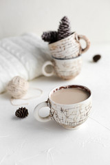 A cup of coffee with milk and a cosy wool plaid on the white concrete table in the morning. Winter or autumn season.