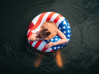 Girl wearing hat in American Flag float in lake