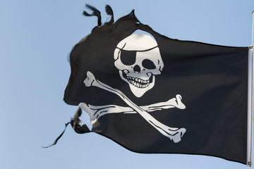 Torn pirate flag against the blue sky