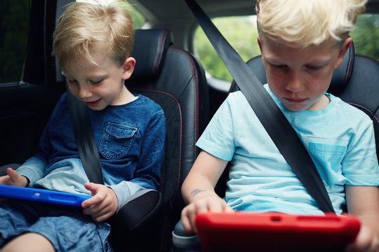 Children using electronic tablets while sat in the car