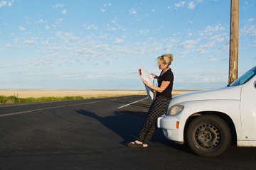 woman looks at map on side of road