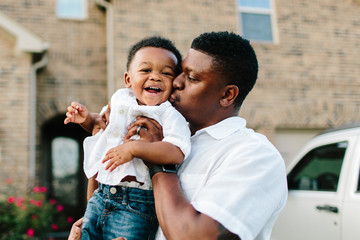 A father giving his 1 year old son a kiss / showing love & affection