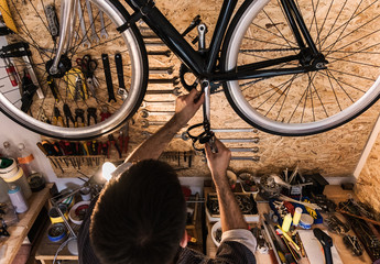 Young mechanic working on bike maintenance in his rustic workshop.