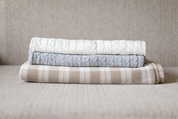 Fototapeta na wymiar Woolen plaids or sweaters on a grey sofa, winter or autumn season.