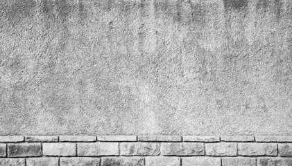 Gray grungy concrete wall with brick base