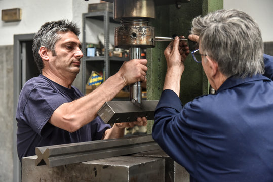 Two men working with an hydraulic press