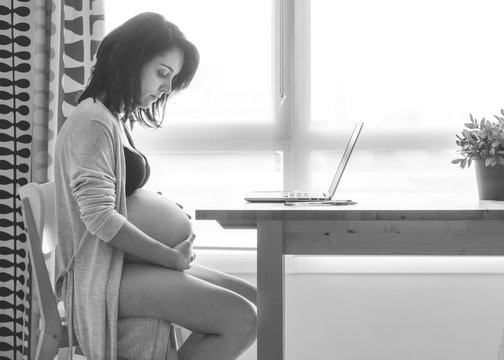 Pregnant working with the computer in the living room