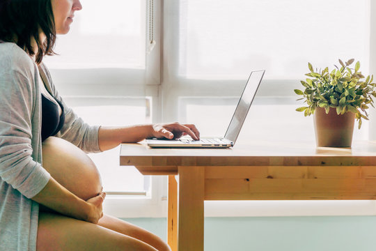 Pregnant working with the computer in the living room