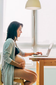 Pregnant working with the computer in the living room