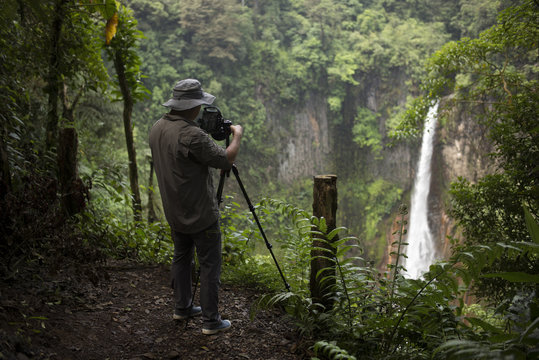 A man take photo for the waterfall in the rain forest