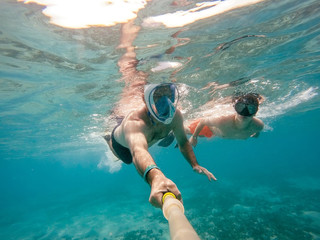 father and son snorkel in shallow water on coral fish