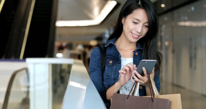 Woman using cellphone and holding shopping bags