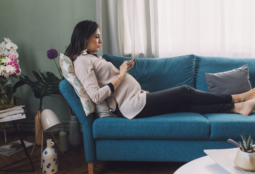 Pregnant Woman Texting on a Couch
