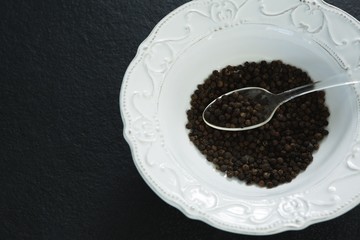 Black pepper in spoon and bowl