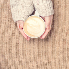 Girl holding cup of coffee with latte art. Leasure time concept. Pastel colors