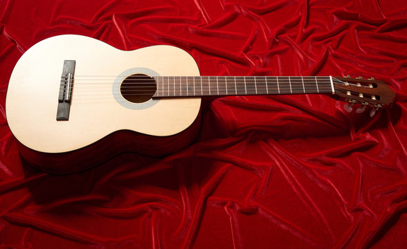 acoustic guitar on red velvet fabric, close view of object