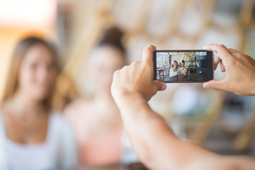 A friend taking photo of two beautiful young women