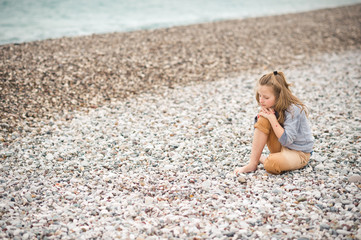 The girl is resting on a pebble sea beach 8207.