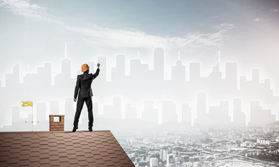 Man architect draw silhouette of modern city on blue sky. Mixed 