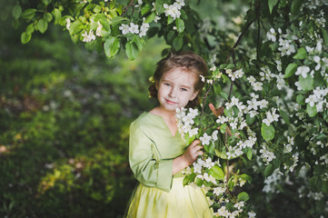 Portrait of a child standing near the branches of the cherry blo