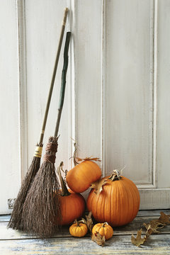 Brooms and pumpkins in front of door