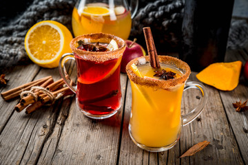 Traditional fall and winter drinks and cocktails. White and red autumn hot spicy sangria with anise, cinnamon, apple, orange, wine. In glass mugs, old rustic wooden table. Selective focus copy space