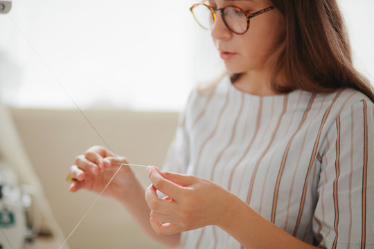 Young Woman In Retro Glasses Unravels The Thread