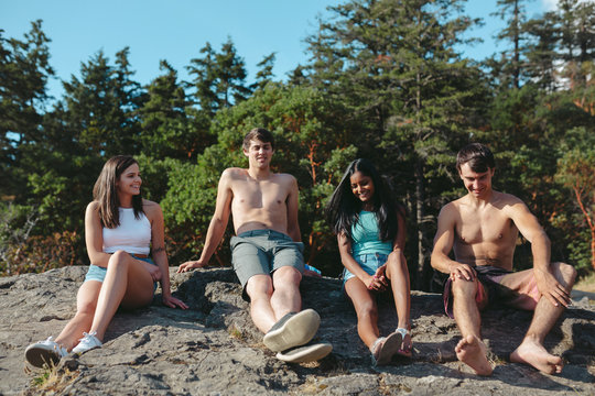 Young, happry friends hanging out on sunny rock in summer