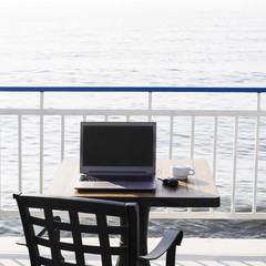 workplace on the beach. computer with a black screen on the desk