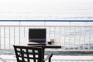 workplace on the beach. computer with a black screen on the desk