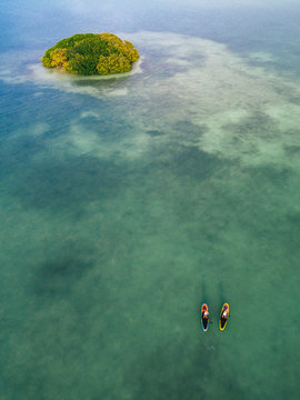 Aerial drone image of two women stand up paddleboarding in the ocean