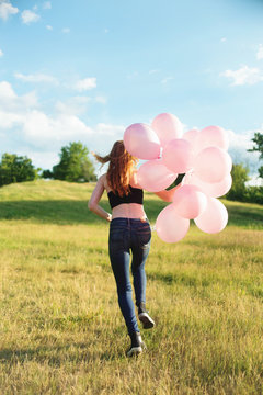 A teenage girl holding balloons in the summertime