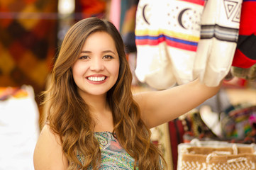 Close up of a beautiful woman holding an andean traditional handbag clothing textile yarn and woven by hand in wool, colorful fabrics background