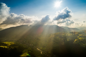 Beautiful panoramic view from the air to the Carpathian Mountains with clouds and sun rays in the foreground